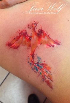 a woman's thigh with watercolor tattoos on her legs and an orange bird