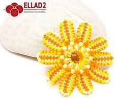 an orange and yellow beaded flower brooch sits on top of a white hat