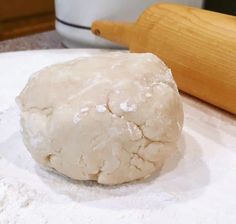 a ball of dough sitting on top of a table next to a wooden rolling pin