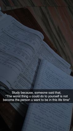 an open book sitting on top of a wooden table next to a pile of papers