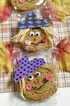 three cookies decorated like scarecrows sitting on top of a checkered table cloth