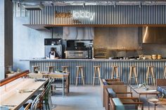 the interior of a restaurant with wooden tables and stools in front of an open kitchen