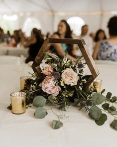 flowers and greenery are on the table in front of people at a wedding reception