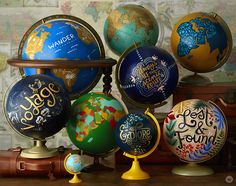 there are many different colored globes on the table with words painted all over them