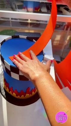 a woman's hand on top of a blue and red cake