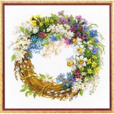 a cross stitched wreath with flowers and leaves on the front, in a gold frame