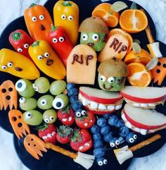 a plate filled with fruit and veggies that have faces drawn on them to look like monsters