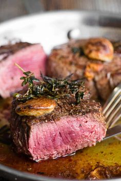 a close up of a steak on a plate with a fork and sauce in it