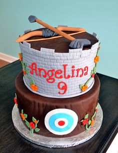 there is a birthday cake with an archery theme on the top and two arrows in the middle