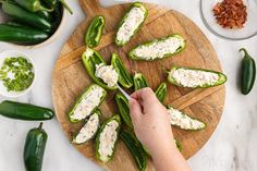 a person cutting up some green peppers on a wooden board with other ingredients around them