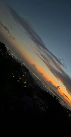 the sun is setting behind some clouds in the sky over a cityscape and hills