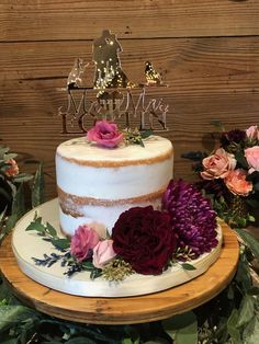 there is a cake with flowers on the plate next to it and a wooden table