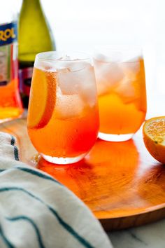 two glasses filled with orange juice next to an orange slice