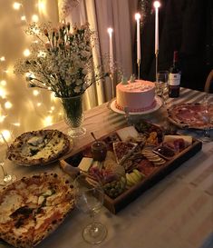 a table topped with lots of food next to a cake and wine glass on top of a table