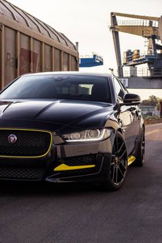 a black and yellow car parked on the side of a road next to a train