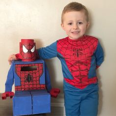 a young boy in spiderman costume standing next to a toy