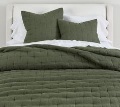 a bed with green bedspread and two pillows