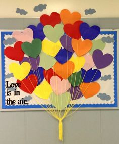 a bunch of heart shaped balloons in front of a sign that says love is in the air