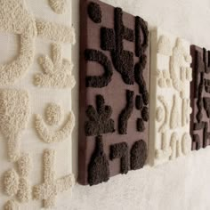 three decorative wall hangings on the side of a white wall with black and brown designs