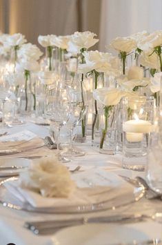 the table is set with white flowers and silverware for an elegant dinnereon party