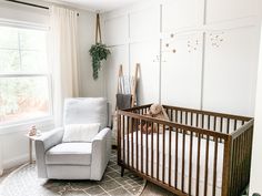 a baby's room with a crib, chair and window