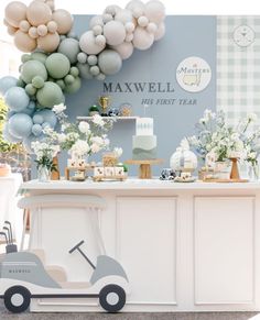 a baby's first birthday party with balloons, cake and desserts on display