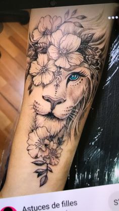 a lion with blue eyes and flowers on his arm is seen in this tattoo artist's photo