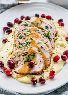 sliced pork with gravy and cranberries on mashed potatoes