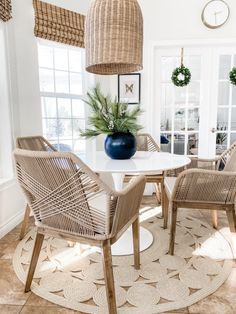 a dining room with wicker chairs and a white table in the middle of it