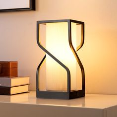 a table lamp sitting on top of a white shelf next to a stack of books