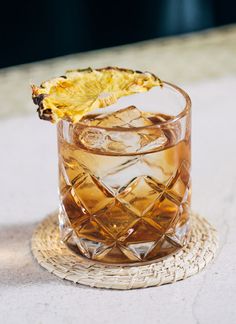 a glass filled with ice sitting on top of a table next to a slice of fruit