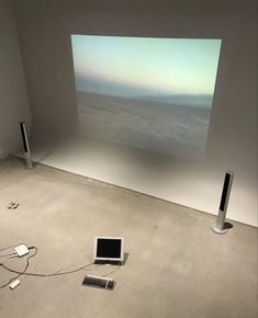 an empty room with two speakers and a laptop on the floor