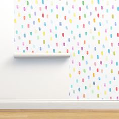 a white wall with multicolored dots on it next to a roll of toilet paper