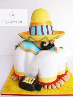 a cake made to look like a man wearing a hat and sitting on a yellow mat