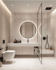 a modern bathroom with round mirrors and white fixtures