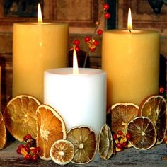 three candles with orange slices and berries around them