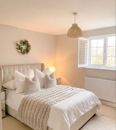 a white bed sitting next to a window in a bedroom