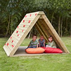 three children sitting in a wooden play structure