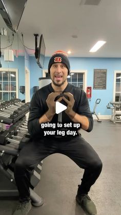 a man sitting on top of a bench in a gym holding his hands up to the camera