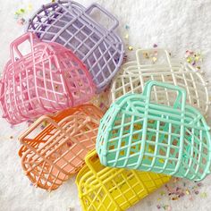 four different colored plastic baskets sitting on top of a white surface with confetti all around them