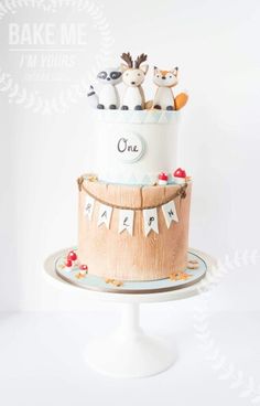 a three tiered cake decorated with animals and bunting on a plate in front of a white background