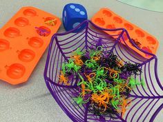 two plastic trays filled with spider web toys on top of a table next to an ice tray