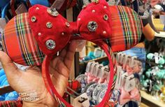 a person is holding up a red minnie mouse ears with bows and jewels on them