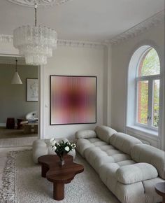 a living room filled with furniture and a large painting hanging on the wall above it