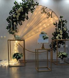 three tables with flowers and cake on them in front of a wall decorated with lights