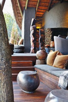 an outdoor living area with wood flooring and large vases on the table next to it