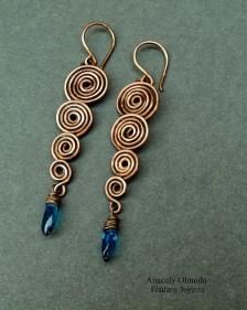 the earrings are made with copper wire and blue glass beads, which have spiral designs on them