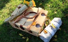 a picnic basket with napkins and flowers in it on the grass next to a roll of toilet paper