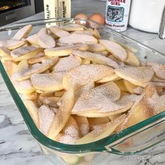 a glass casserole dish filled with cookies and powdered sugar