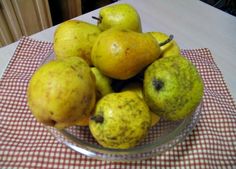 a glass bowl filled with pears on top of a table